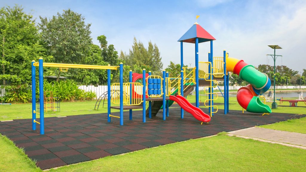 Outdoor custom playground surrounded by green grass and blue skies