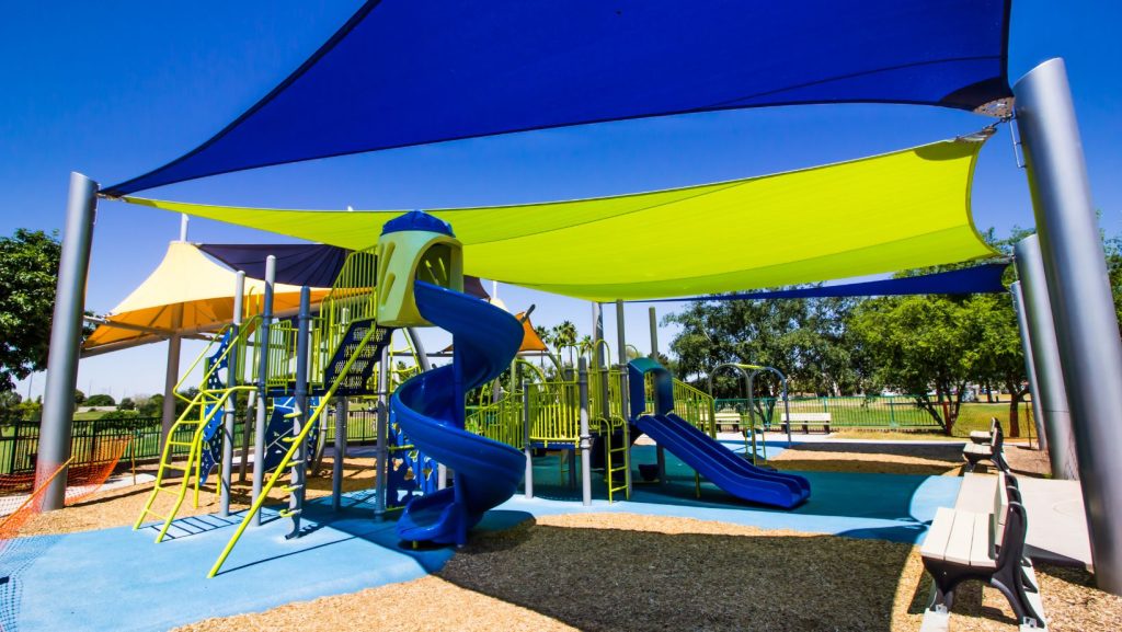 Outdoor playground with a shade structure over top of it